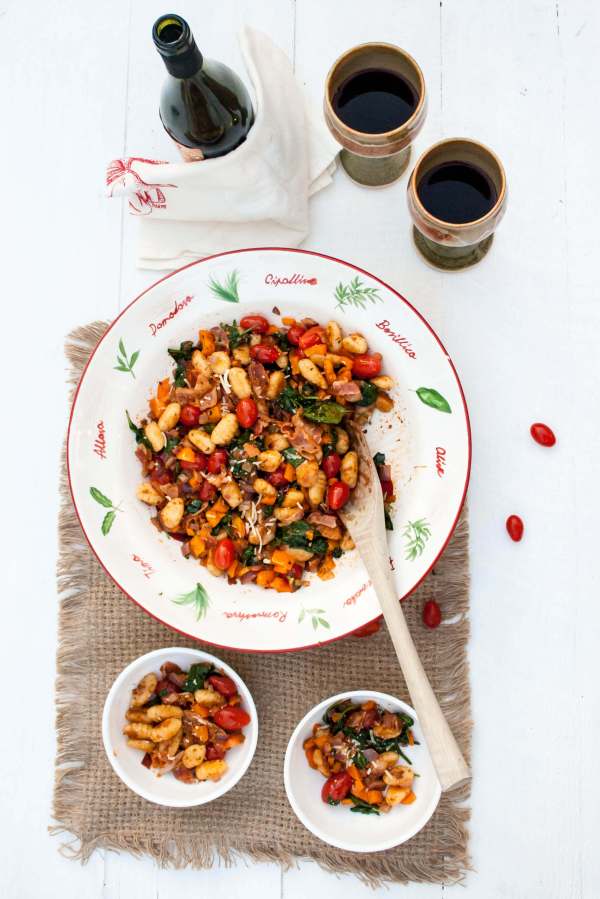 Gnocchi fried in a skillet with cherry tomatoes, bacon, spinach, yellow peppers and pesto. What a great weeknight meal!