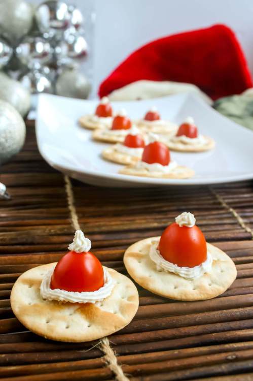 Santa Hats made with cherry tomatoes and cream cheese on a cracker. A simple, cute, and healthy Christmas appetizer!